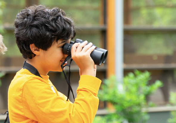 School students outdoors looking through binoculars